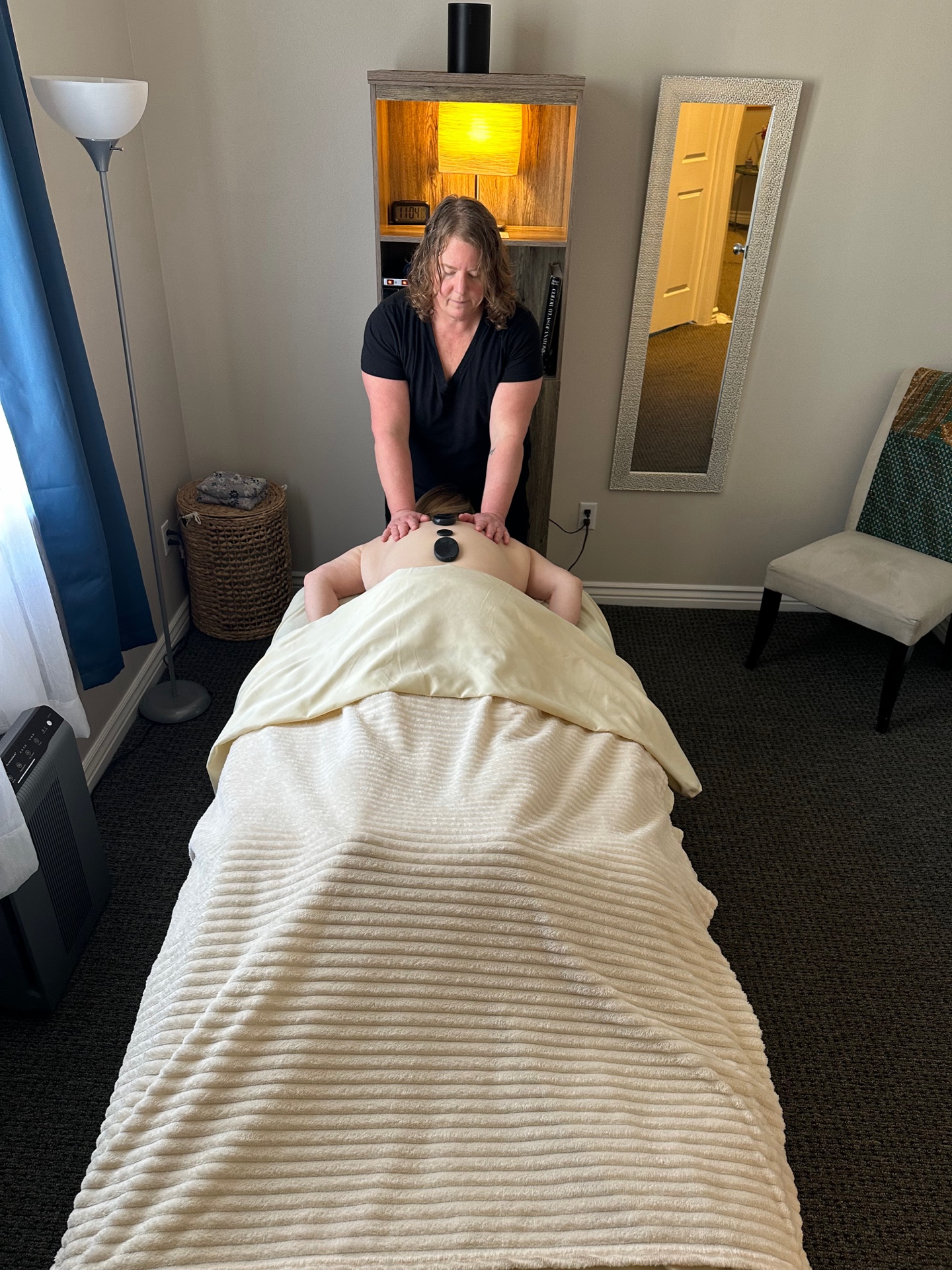 Liz Moffat providing hot stone massage therapy in her Murray Utah treatment room
